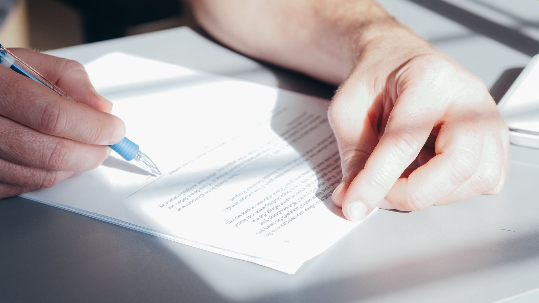 Manos rellenando un formulario sobre una mesa