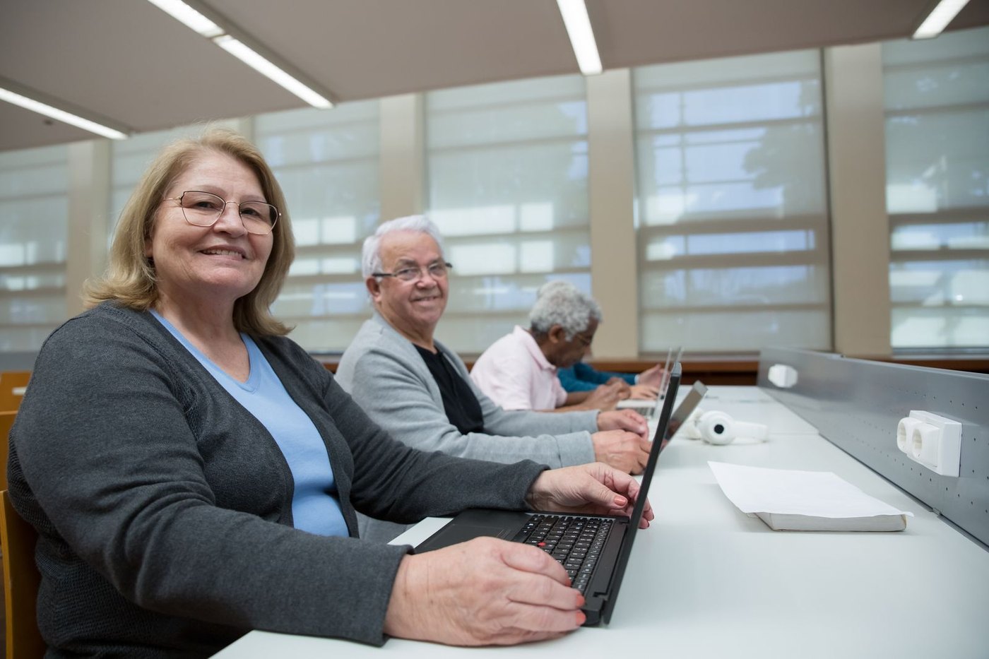 Personas adultas trabajando con ordenadores portátiles en un aula de formación