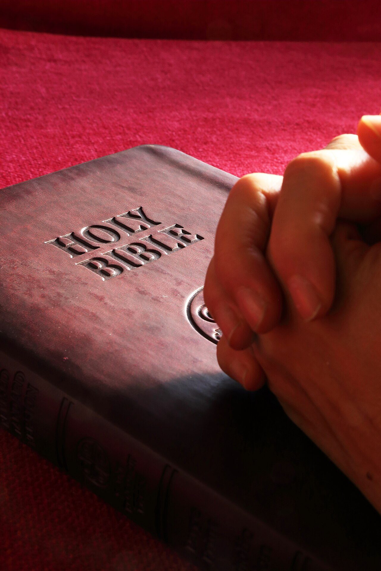 Manos orando sobre una Biblia