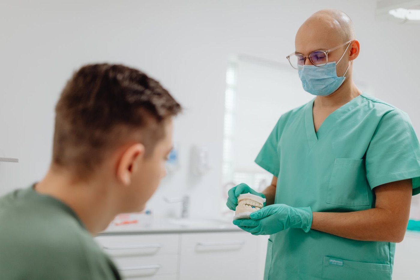 Un odontólogo explica a un paciente sobre una maqueta dental en la consulta