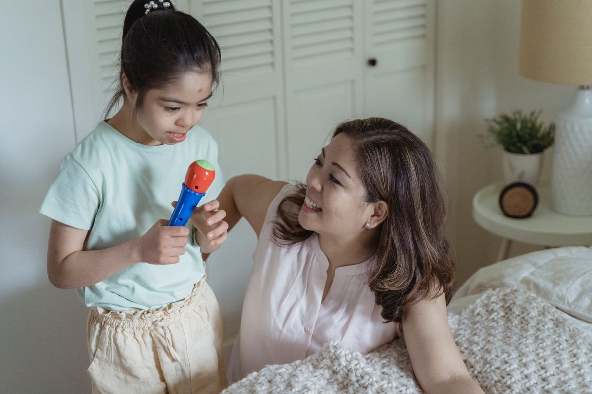 Una madre habla con su hija pequeña sentadas en la cama