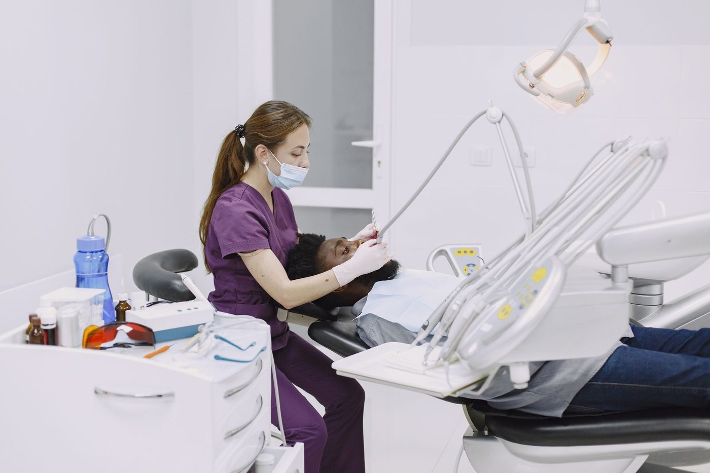 Una odontóloga revisa la boca de un paciente sentado en el sillón dental