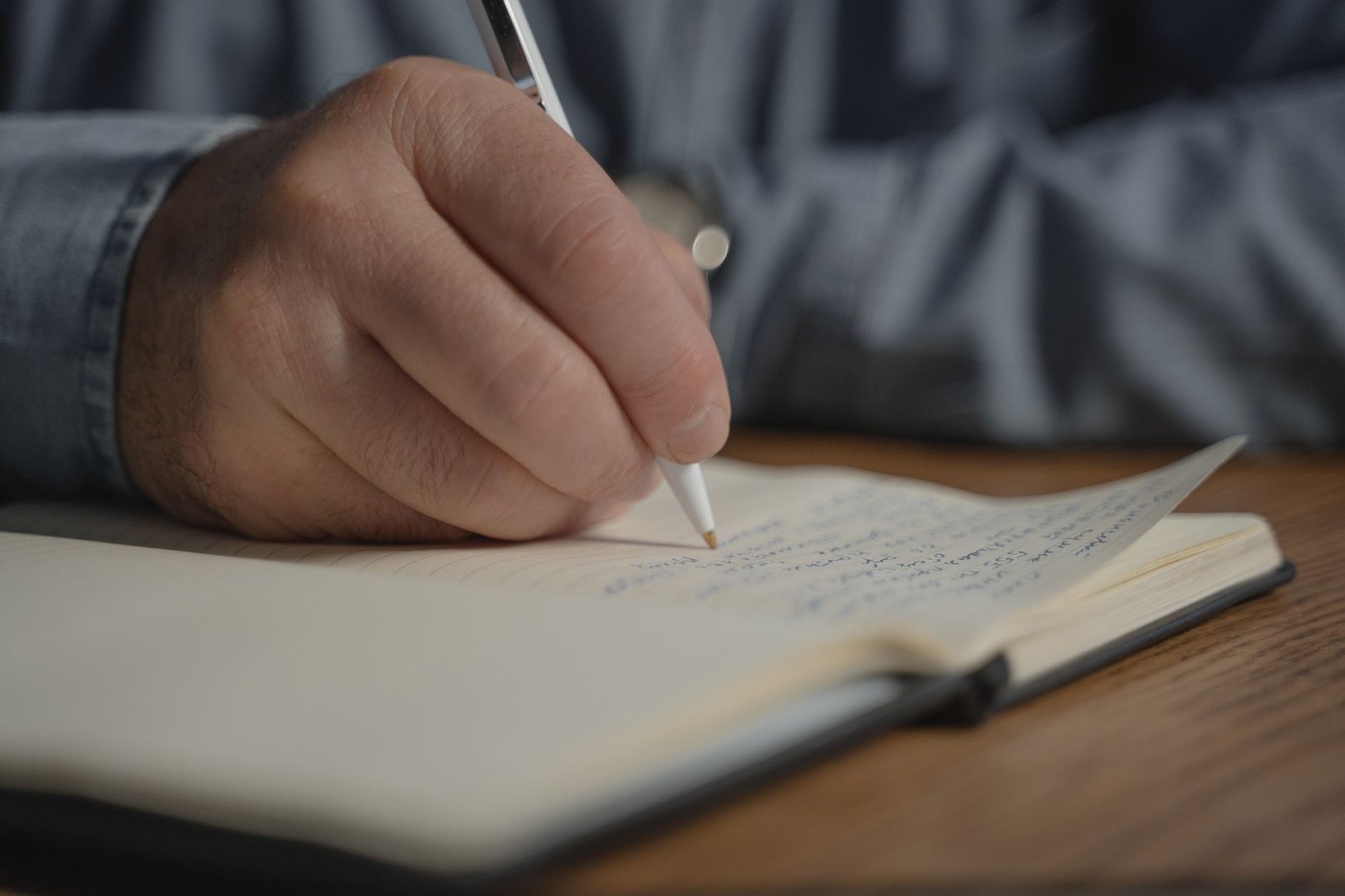 Una mano escribe a bolígrafo en un cuaderno abierto