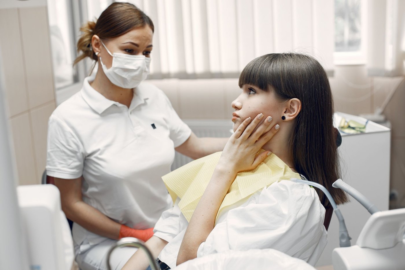 Una paciente se lleva la mano a la mandíbula en el sillón del dentista