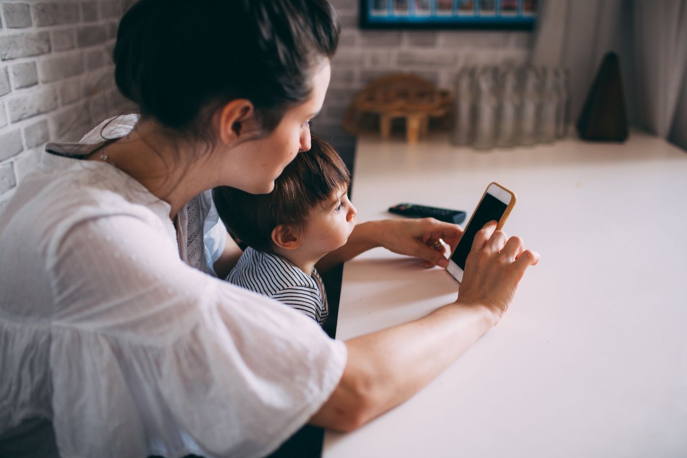 Una madre con su hijo pequeño mirando el móvil en casa