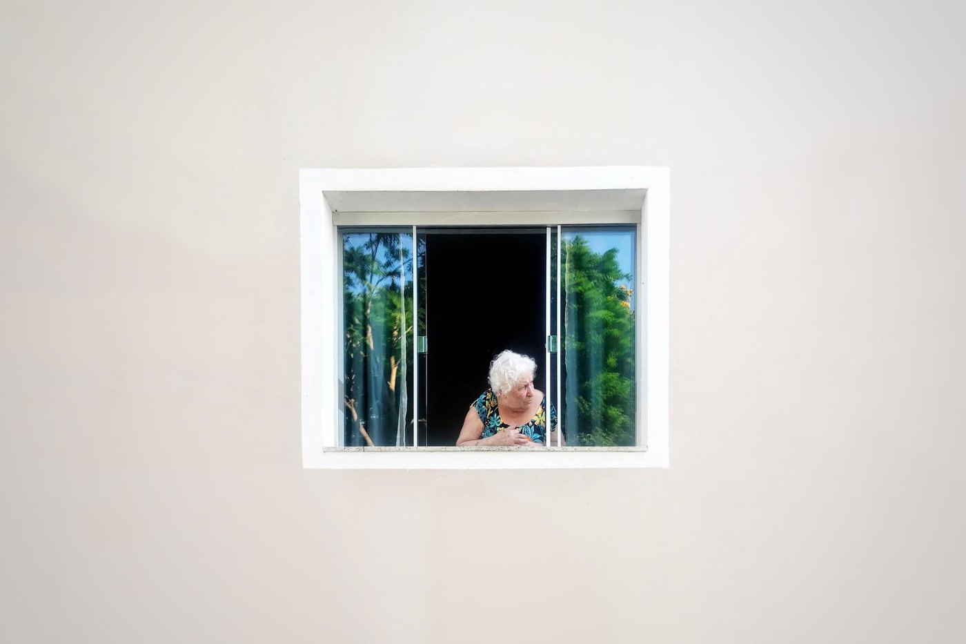 Una mujer mayor se asoma a la ventana de su casa