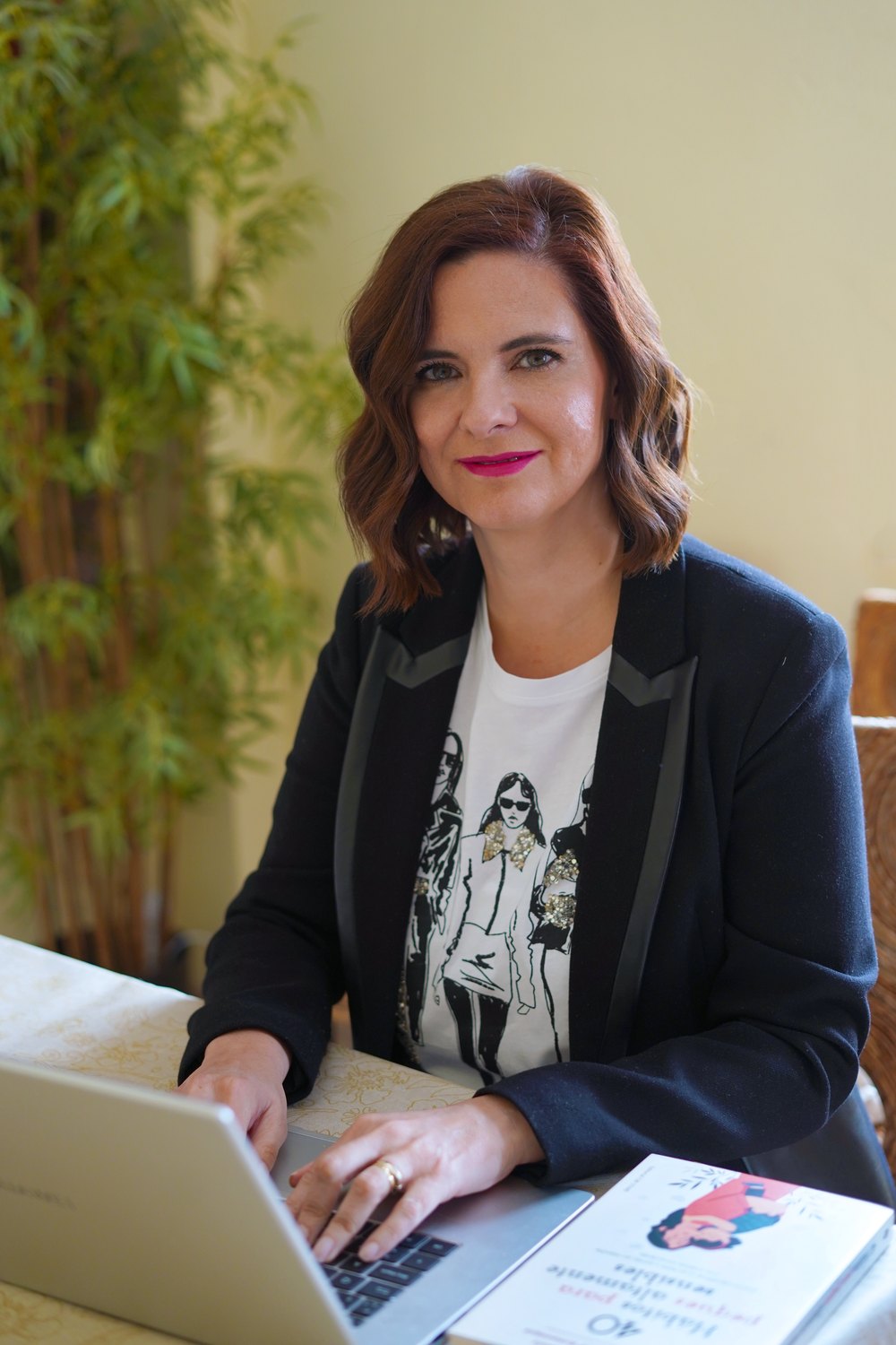Rosario Jiménez escribiendo en su portátil junto a su libro