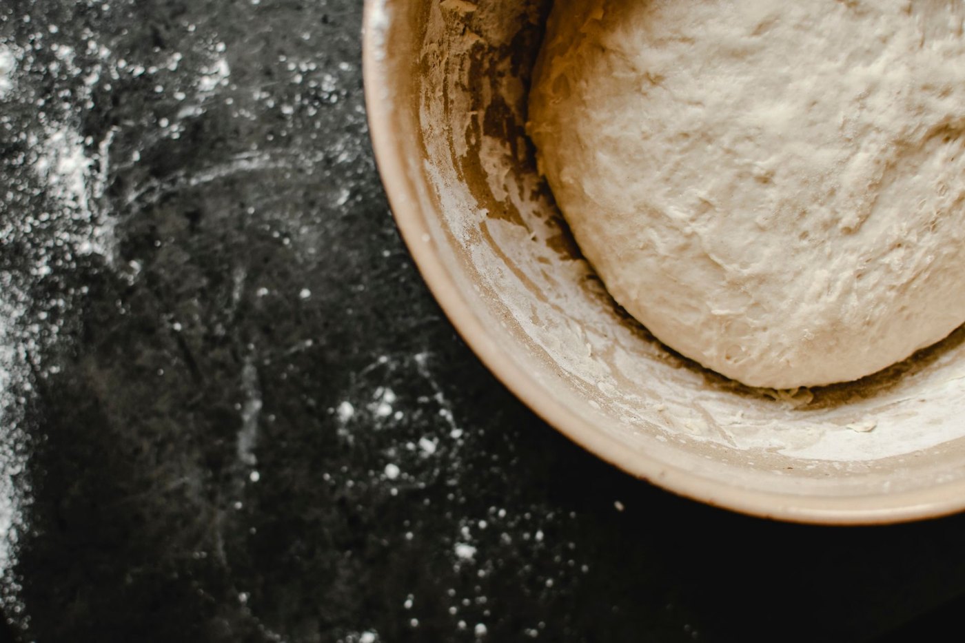 Masa de pan fermentando en un cuenco sobre una mesa enharinada