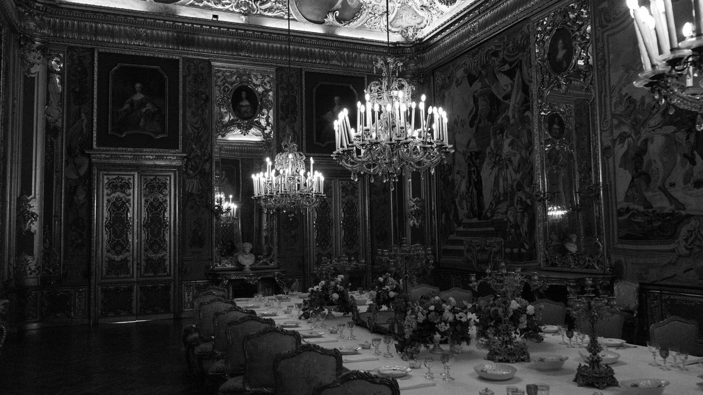 Salón de palacio con lámparas de araña y una larga mesa de banquete