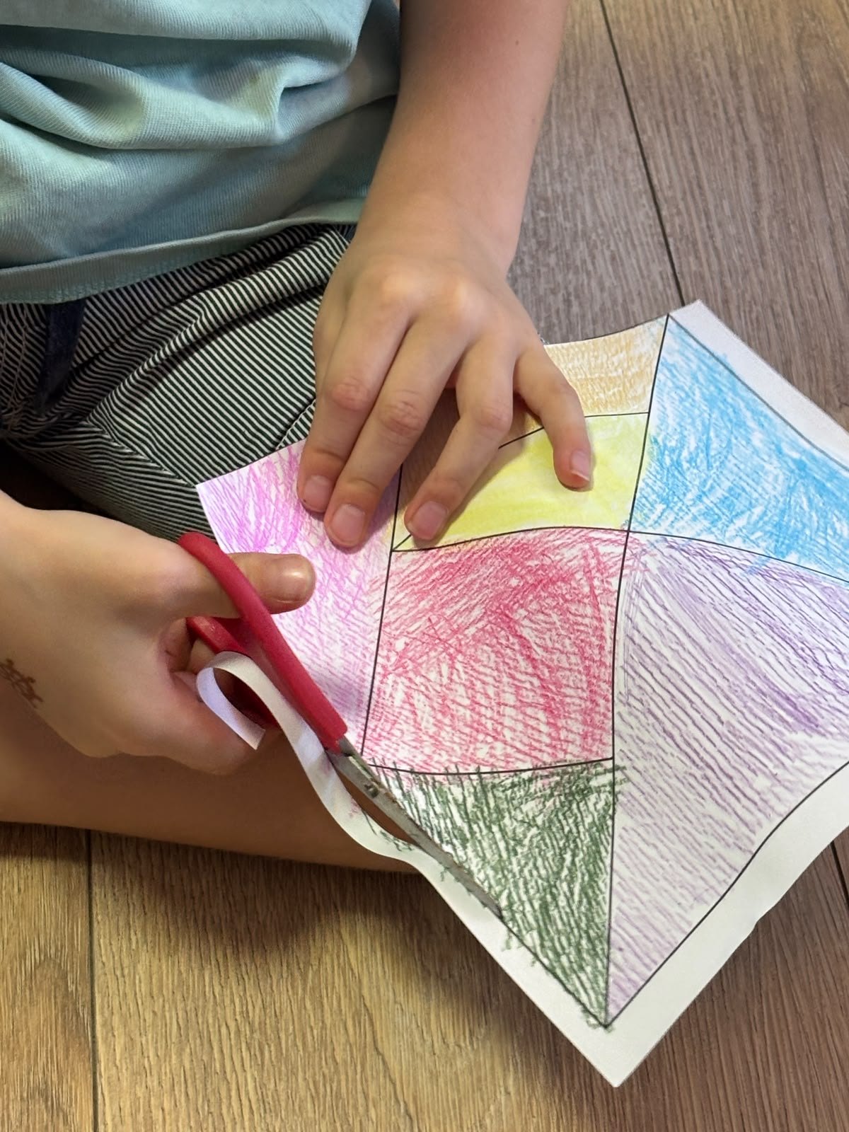 Un niño recorta las piezas de un tangram coloreado