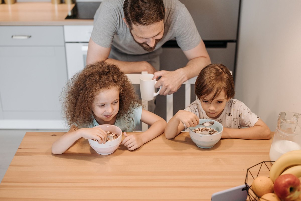 Un padre desayuna con sus dos hijos en la cocina